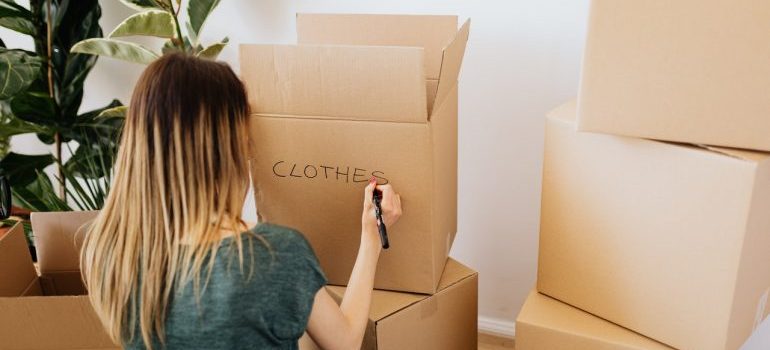 Woman labeling a box as Clothes